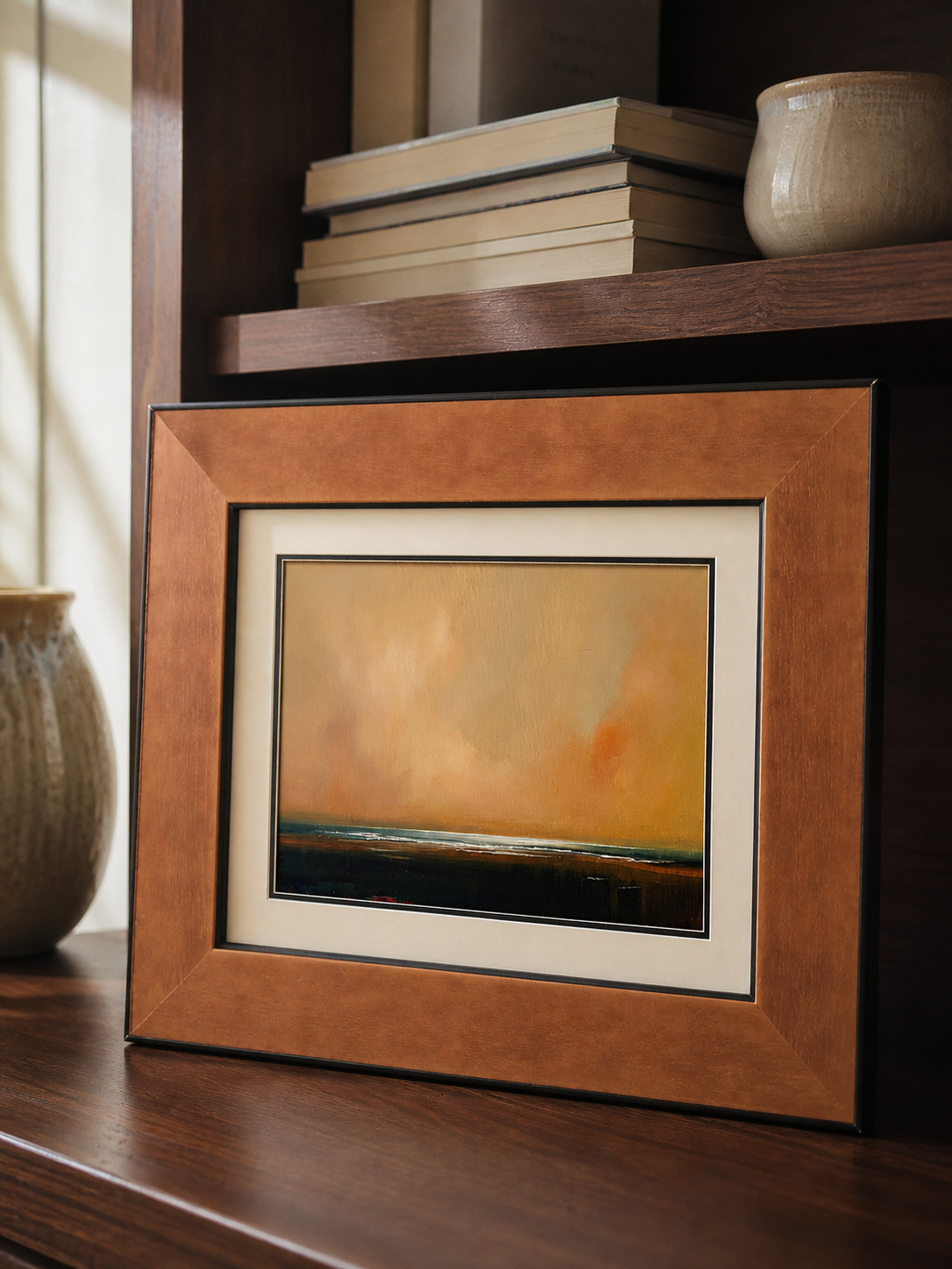 MOOJI ART warm amber landscape framed wall art leaning against a walnut bookcase